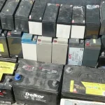 Decommissioned industrial lead acid batteries and backup power modules stacked for chemical extraction loops