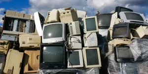 Stack of obsolete CRT computer monitors and old office desktop casings ready for asset recovery segregation