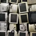 Stack of decommissioned computer CRT monitors and old electronic terminal display scrap ready for safe e-waste recycling.